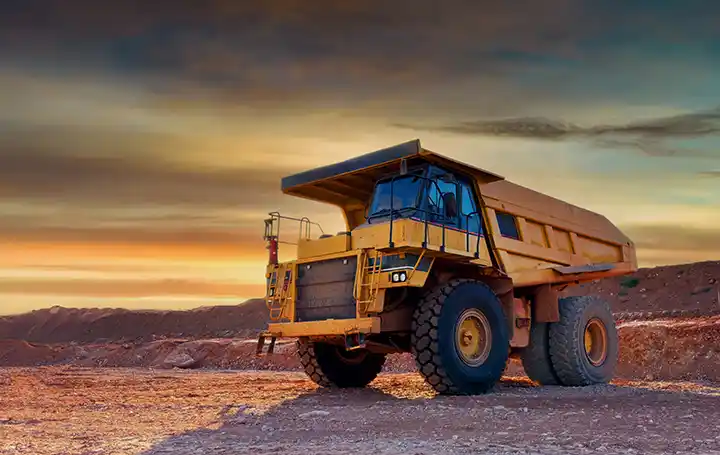 CAT mining haul truck at an open-pit mine during sunset.